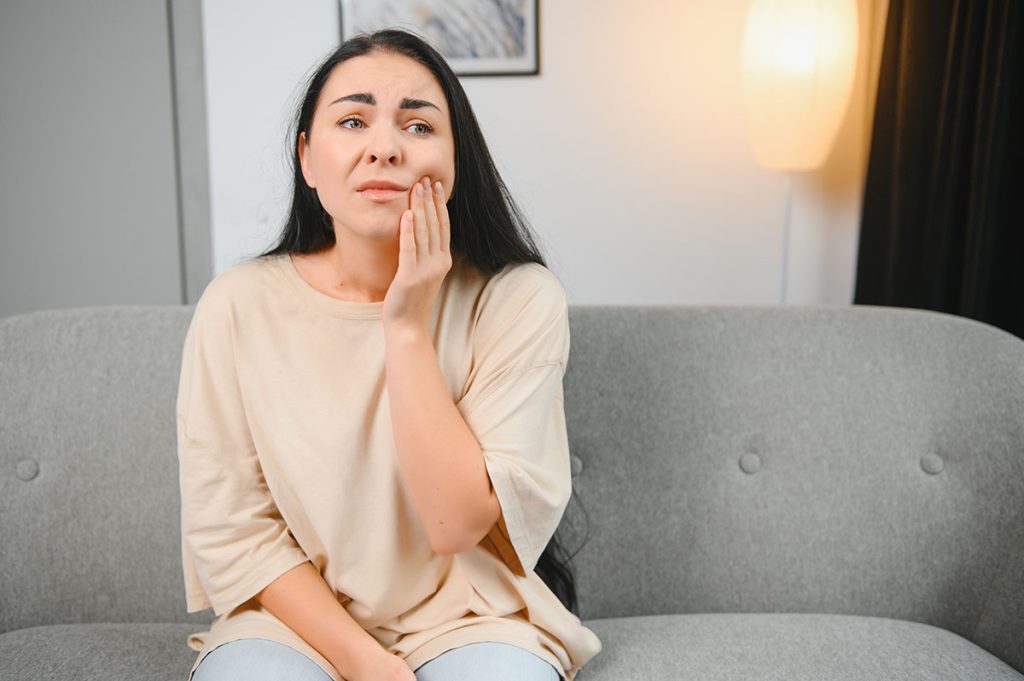 mujer con cara de dolor por encías inflamadas