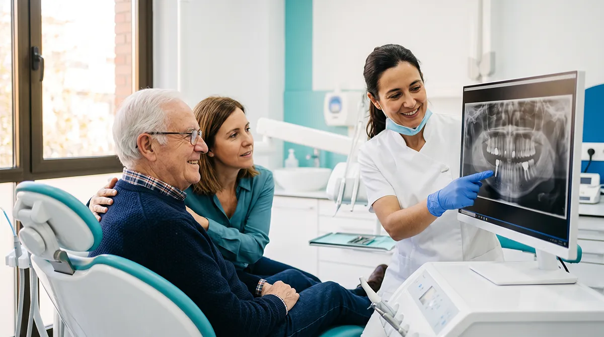 Paciente mayor acompañado por su hija mientras la dentista le explica su radiografía antes de ponerse implantes dentales en la Clínica Dental Bayo Martín de Castro-Urdiales
